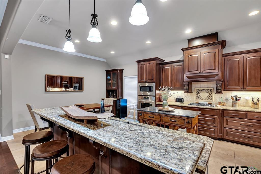 2001 Winding Run Lane Longview, TX 75605 - Photo 35 of 45 a kitchen with stainless steel appliances granite countertop a sink dishwasher a stove a refrigerator a dining table and chairs with wooden floor