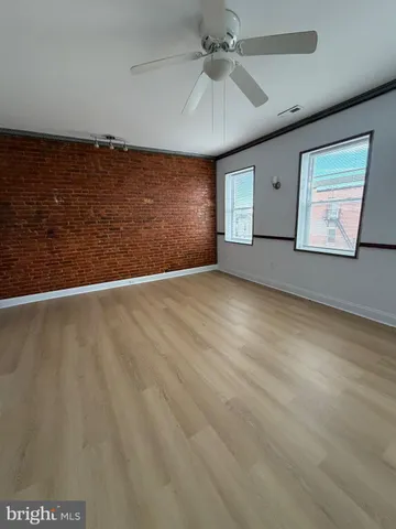 an empty room with windows and fan