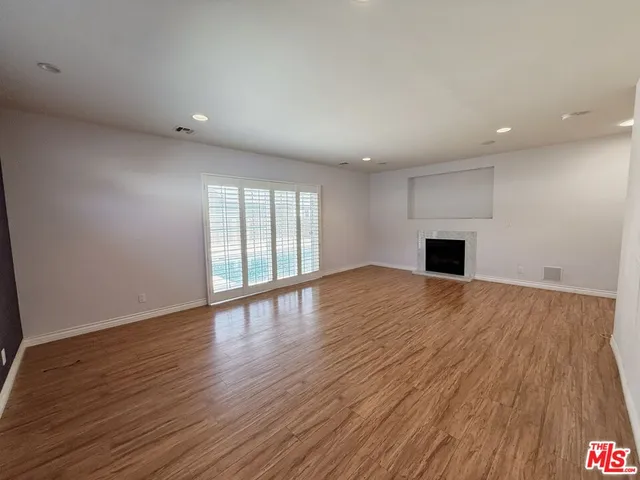 a view of empty room with wooden floor and fireplace