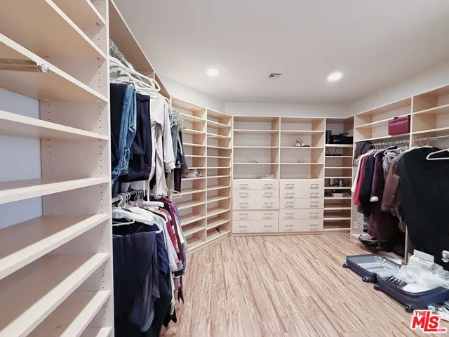 a view of walk in closet with clothes and shoes