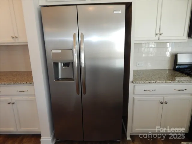a view of a refrigerator in kitchen and white cabinets