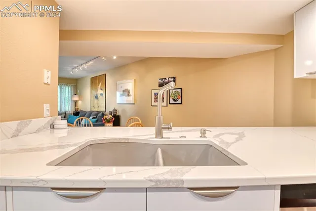 a kitchen with stainless steel appliances granite countertop a dining table chairs and a refrigerator