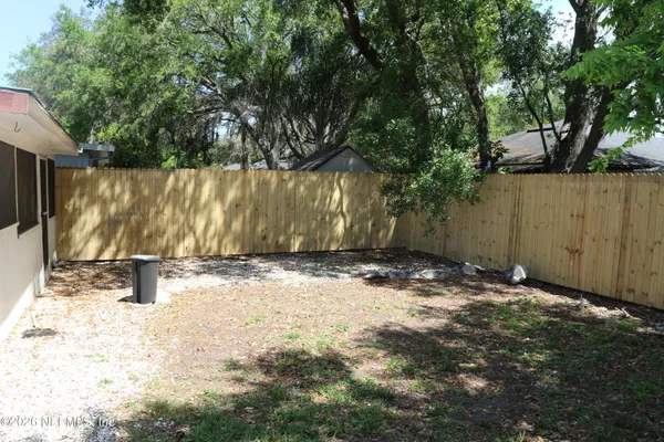 a backyard of a house with a bench and trees