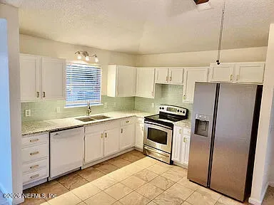 a kitchen with stainless steel appliances granite countertop a sink a stove a refrigerator and island