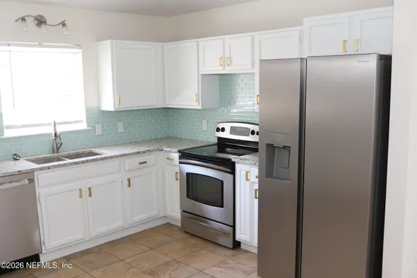 a kitchen with stainless steel appliances granite countertop a refrigerator sink and white cabinets