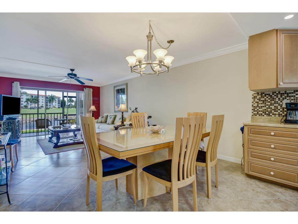 49 High Point Circle South, Unit 102 Naples, FL 34103 - Photo 12 of 31 a view of a dining room with furniture wooden floor and chandelier