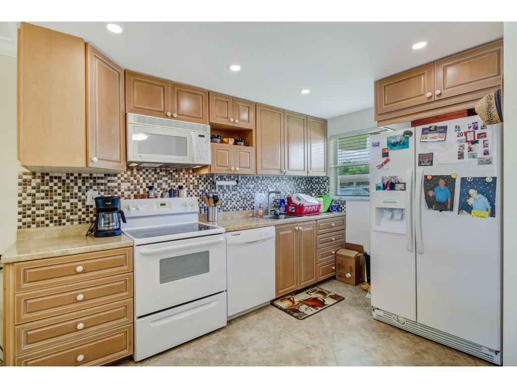 49 High Point Circle South, Unit 102 Naples, FL 34103 - Photo 13 of 31 a kitchen with a refrigerator and cabinets