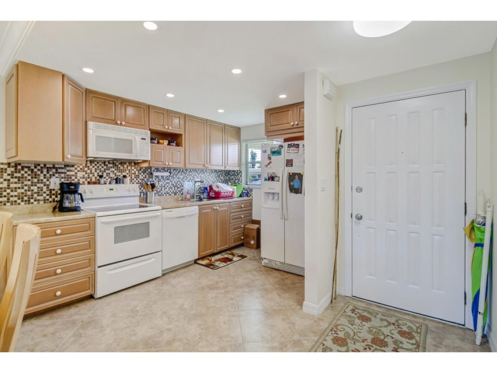 49 High Point Circle South, Unit 102 Naples, FL 34103 - Photo 14 of 31 a kitchen with a refrigerator and white cabinets