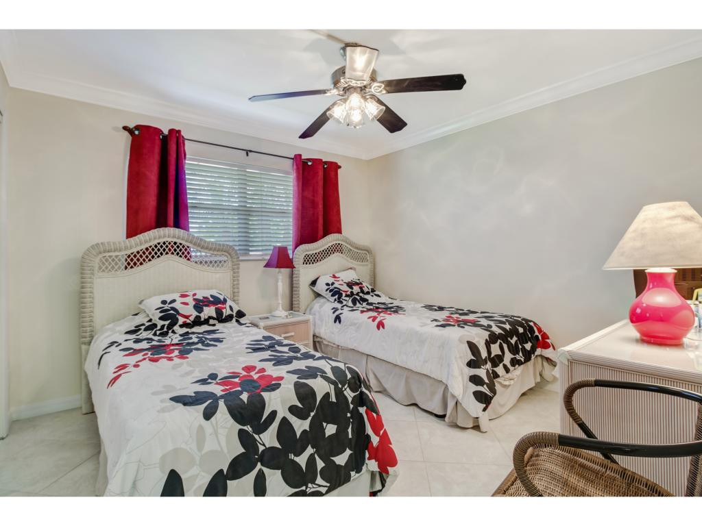 49 High Point Circle South, Unit 102 Naples, FL 34103 - Photo 15 of 31 a bedroom with two bed and a chandelier