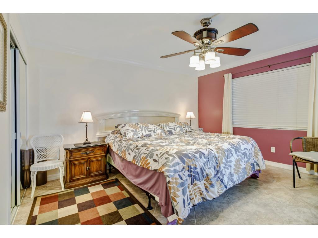 49 High Point Circle South, Unit 102 Naples, FL 34103 - Photo 18 of 31 a bedroom with a bed and a chandelier