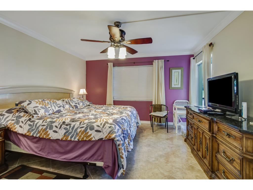 49 High Point Circle South, Unit 102 Naples, FL 34103 - Photo 19 of 31 a bedroom with a bed and a flat screen tv