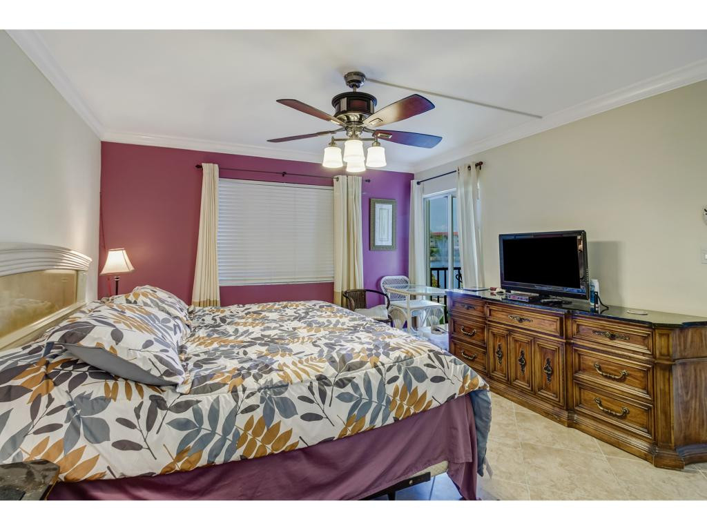 49 High Point Circle South, Unit 102 Naples, FL 34103 - Photo 20 of 31 a bedroom with a bed and a flat screen tv
