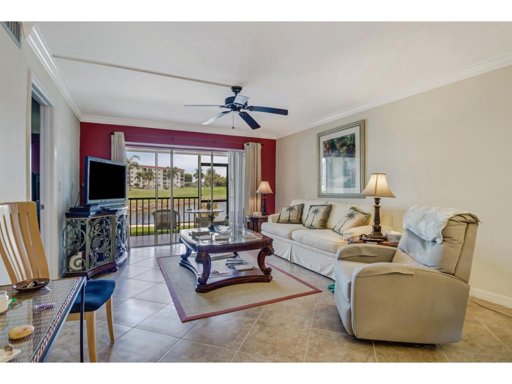 49 High Point Circle South, Unit 102 Naples, FL 34103 - Photo 6 of 31 a living room with furniture a flat screen tv and a large window