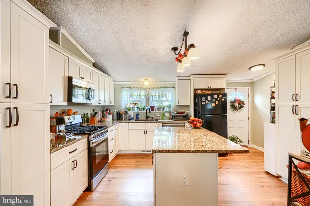 a kitchen with granite countertop a refrigerator stove top oven and sink