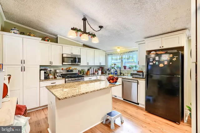a kitchen with kitchen island a counter top space a sink appliances and cabinets