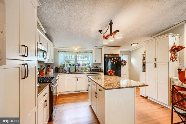 a kitchen with stainless steel appliances granite countertop a refrigerator and a stove top oven