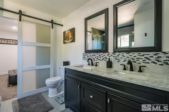 a bathroom with a granite countertop sink a toilet a mirror and shower