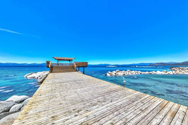 a roof deck with a table and chairs under an umbrella with wooden floor