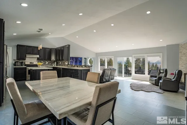 a living room with stainless steel appliances furniture dining table and a large window