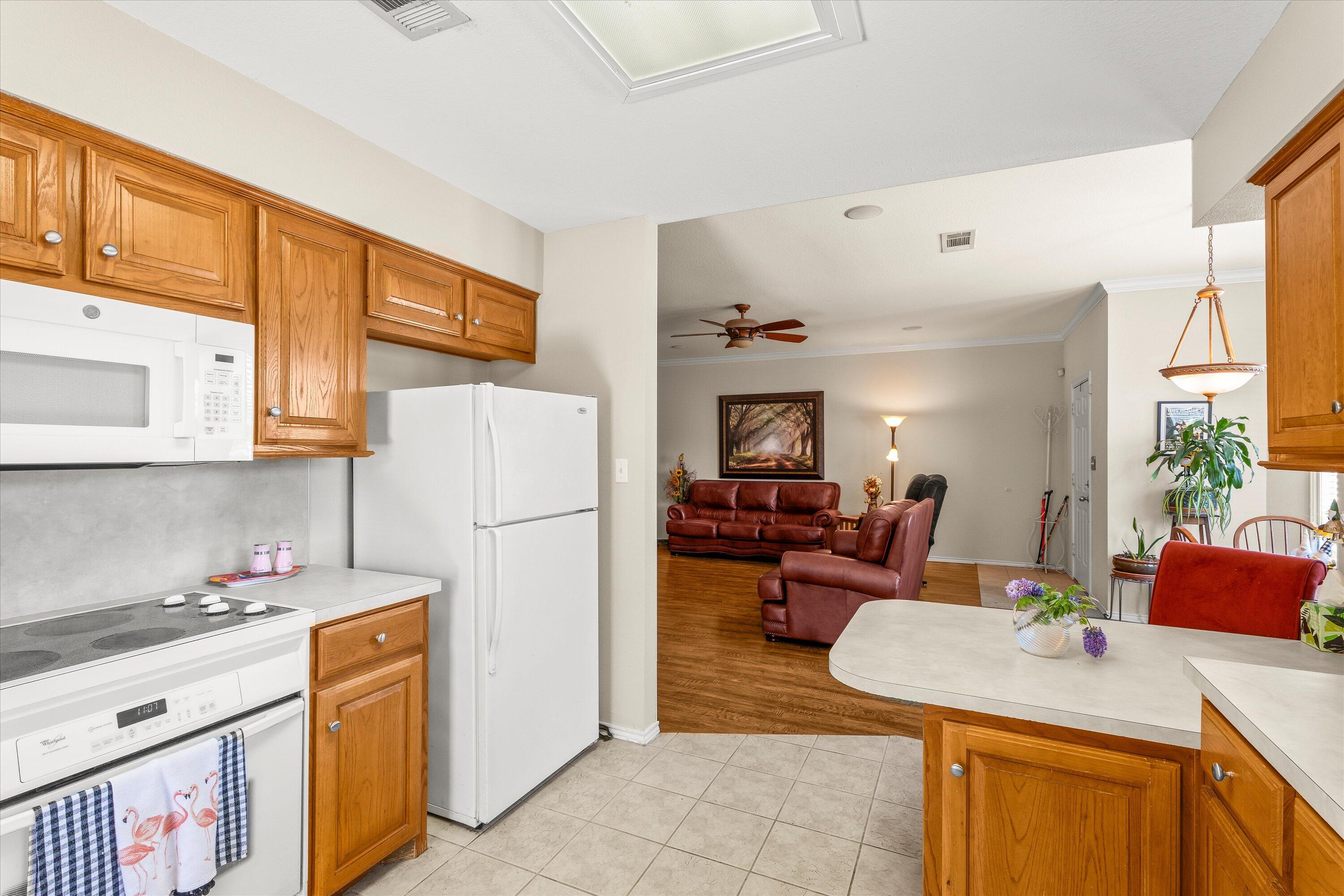 710 Poplar Street Levelland, TX 79336 - Photo 7 of 23 a kitchen with a refrigerator a stove top oven a sink dishwasher and dining table with wooden floor