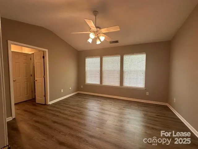 a view of an empty room with window and wooden floor