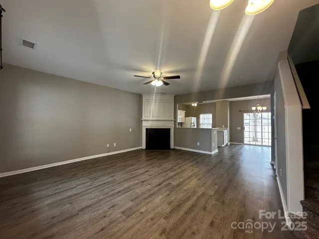 an empty room with wooden floor fireplace and windows