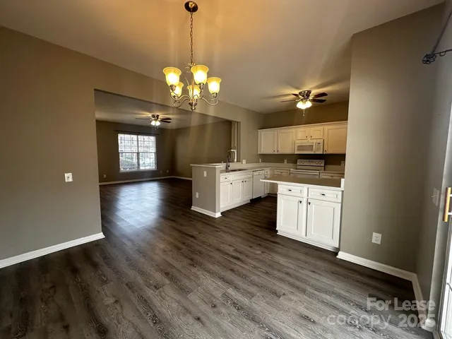 a view of a kitchen with a sink dishwasher a stove and wooden floor