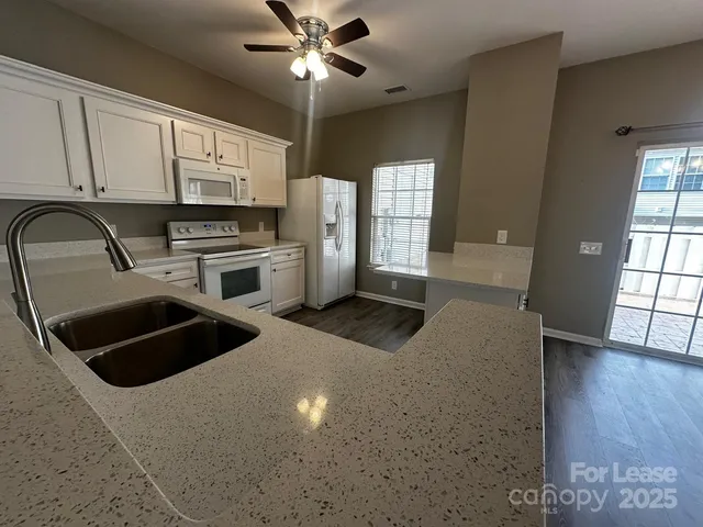 a kitchen with granite countertop a stove a sink and a microwave