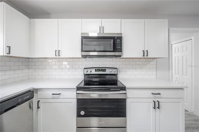 a kitchen with granite countertop white cabinets and stainless steel appliances