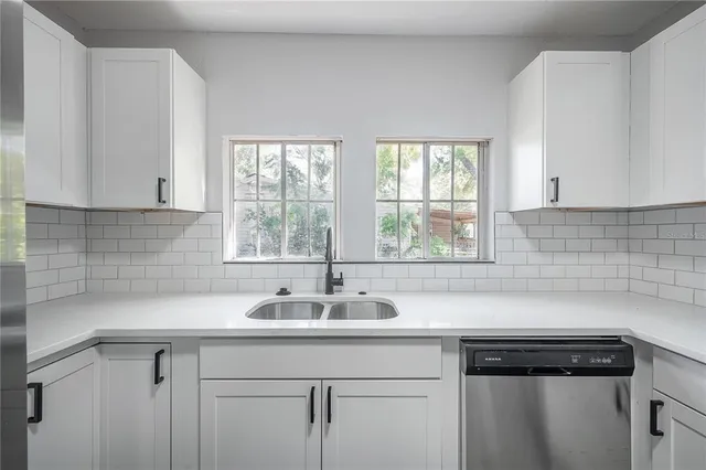 a sink with white cabinets and a window