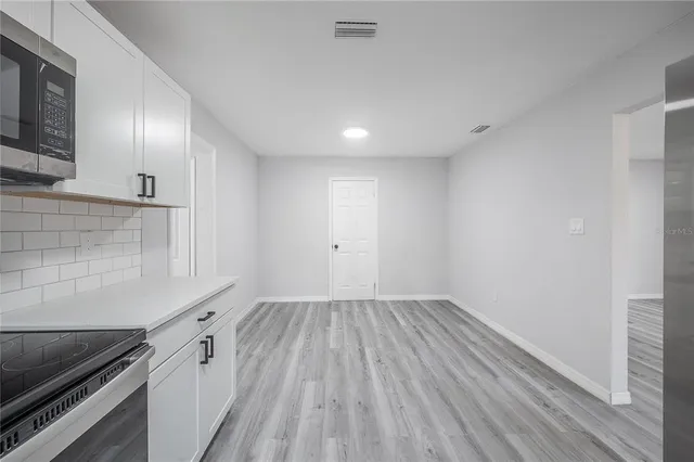 a view of a kitchen with wooden floor and electronic appliances