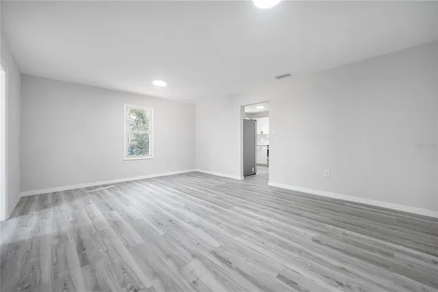 a view of an empty room with wooden floor and a window