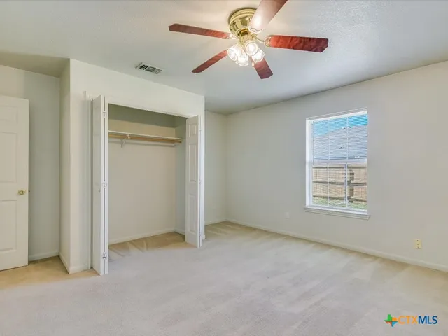 an empty room with windows and fan
