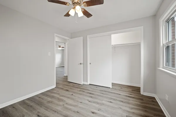 a view of an empty room with wooden floor and window