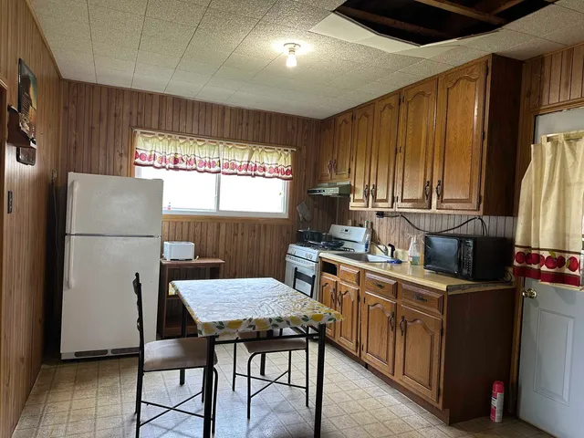 a kitchen with a table chairs refrigerator and window