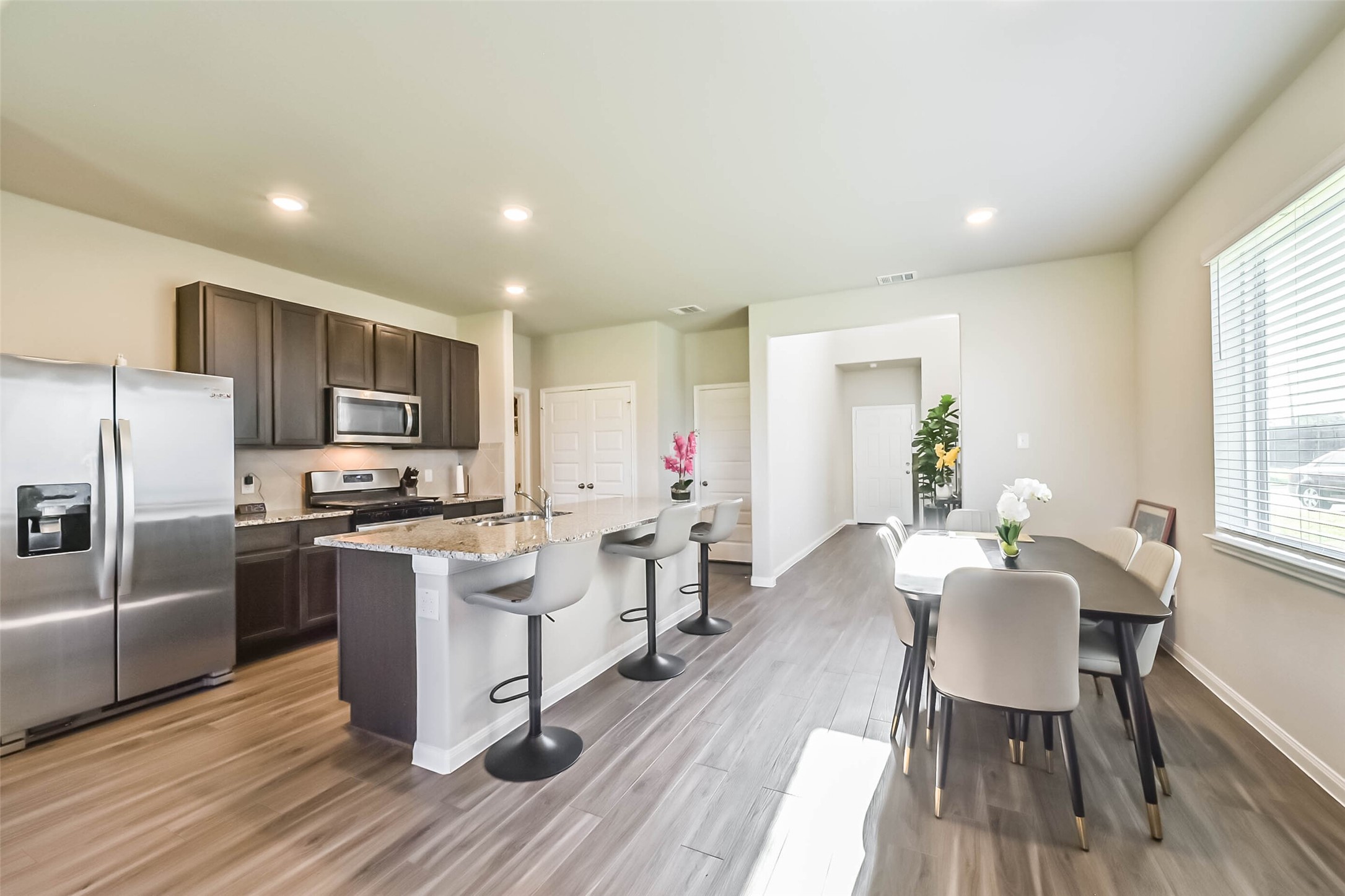4907 Luke Matthew Drive Rosharon, TX 77583 - Photo 9 of 42 a kitchen with stainless steel appliances granite countertop a refrigerator a stove top oven a sink dishwasher a dining table and chairs with wooden floor