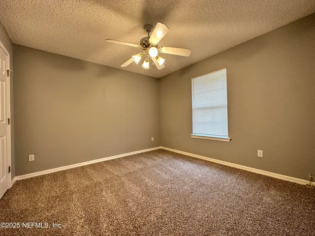 an empty room with a window and a ceiling fan