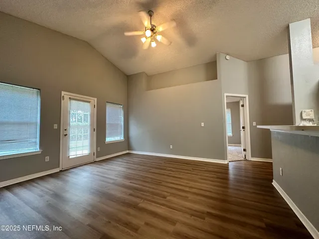 a view of an empty room with window and wooden floor