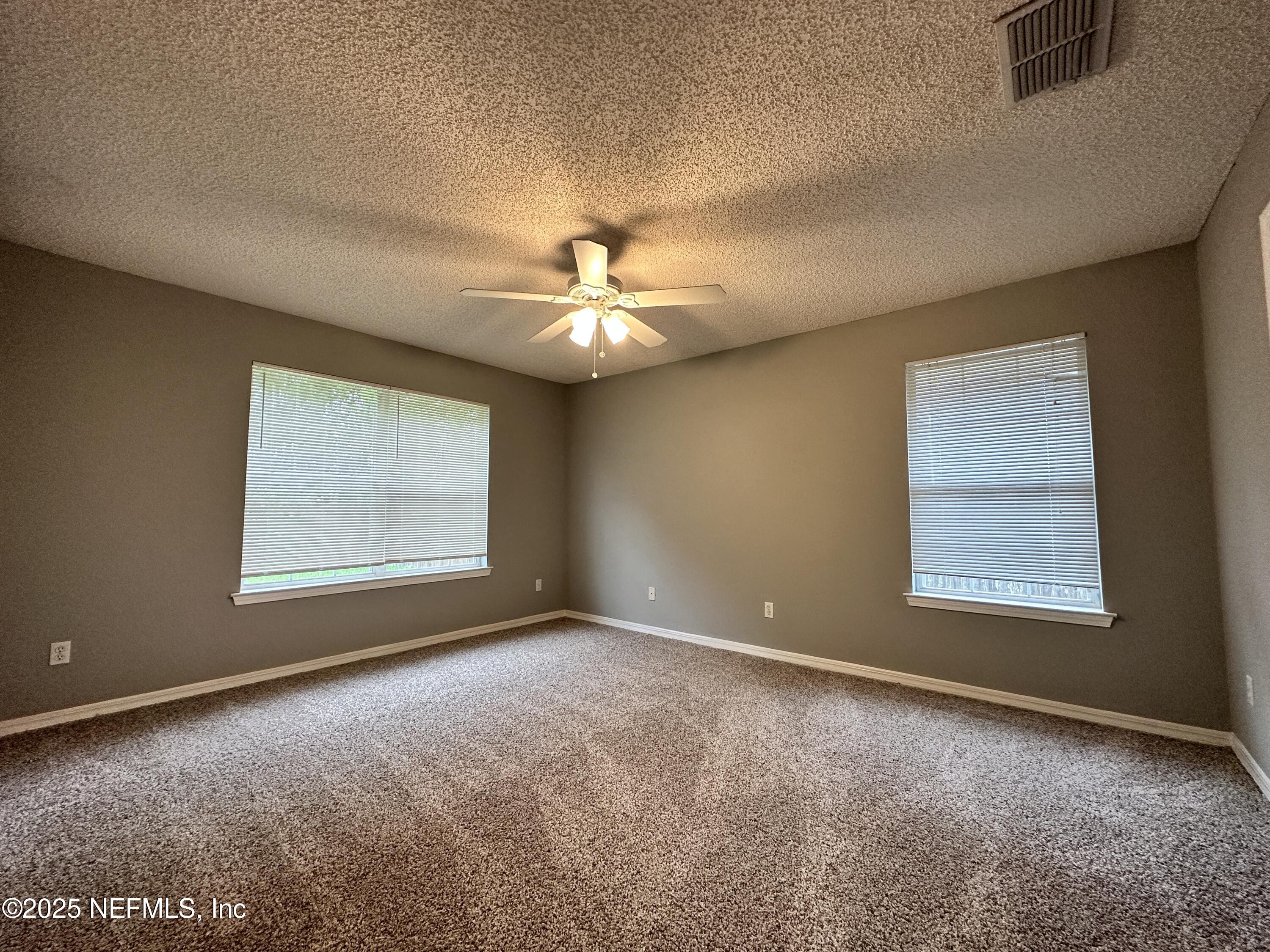 2478 Aloha Lane Middleburg, FL 32068 - Photo 7 of 16 an empty room with windows and chandelier fan