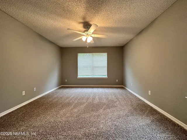 an empty room with windows and fan