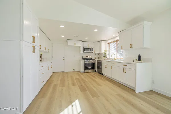 a kitchen with white cabinets appliances and a sink