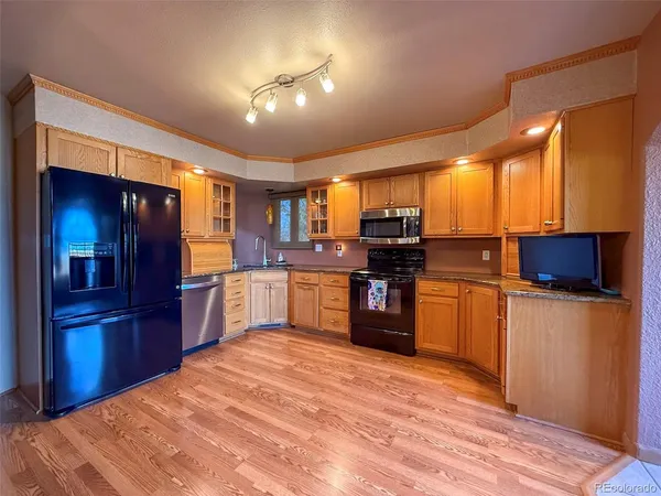 a kitchen with stainless steel appliances kitchen island granite countertop a refrigerator stove top oven and sink