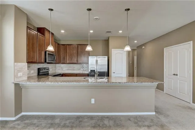 a kitchen with stainless steel appliances granite countertop a refrigerator a stove a sink and a refrigerator