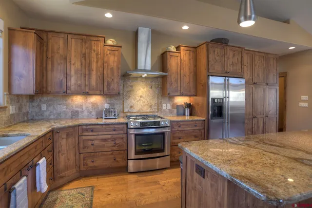 a kitchen with stainless steel appliances granite countertop wooden cabinets a sink and dishwasher with wooden floor