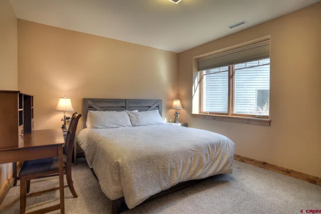 a bedroom with a bed and dresser with chair