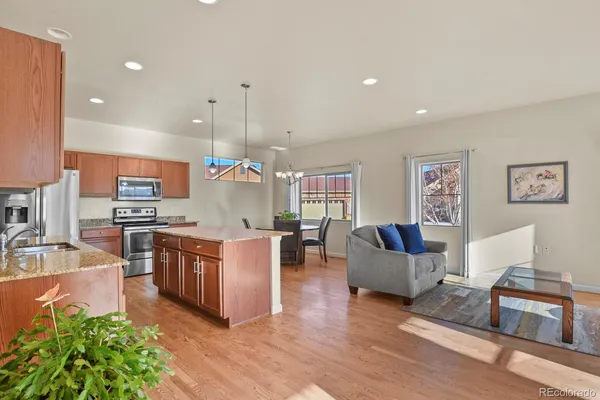 a large living room with stainless steel appliances granite countertop couches a flat screen tv and a refrigerator