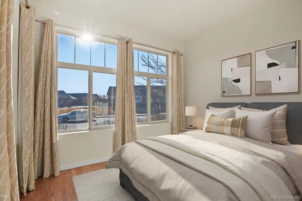 a bedroom with a large window and a wooden floor