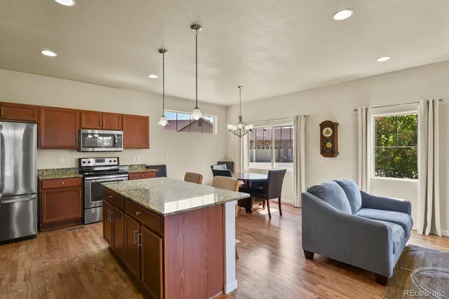 a kitchen with a refrigerator a stove top oven a sink dishwasher and couches with wooden floor