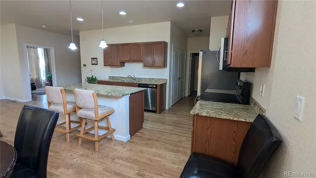 a large kitchen with stainless steel appliances kitchen island granite countertop a table chairs sink and cabinets