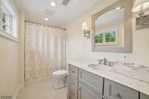 a bathroom with a granite countertop sink a toilet and a mirror